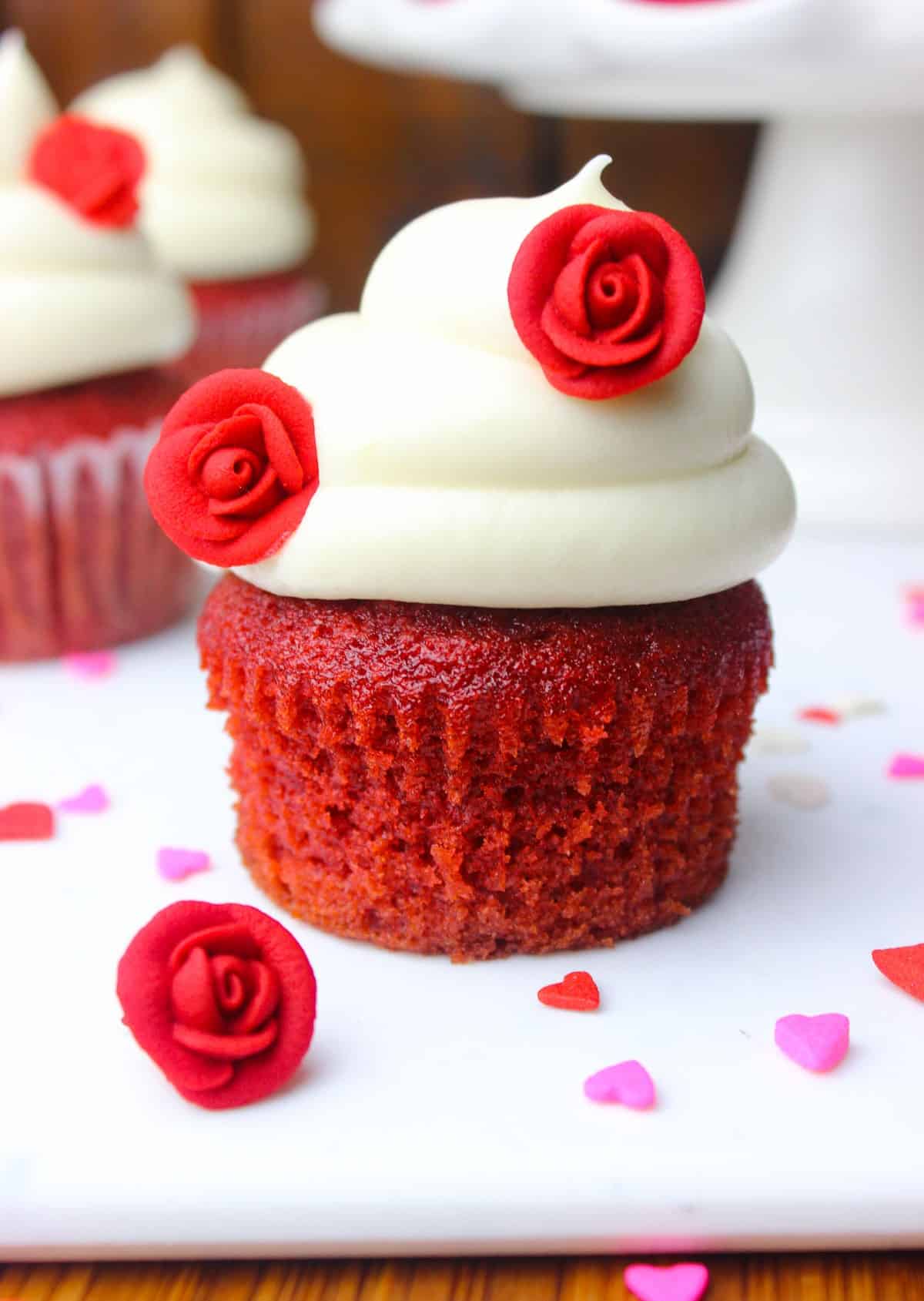 Red velvet cupcake topped with tangy and sweet frosting embellished with sugar roses.