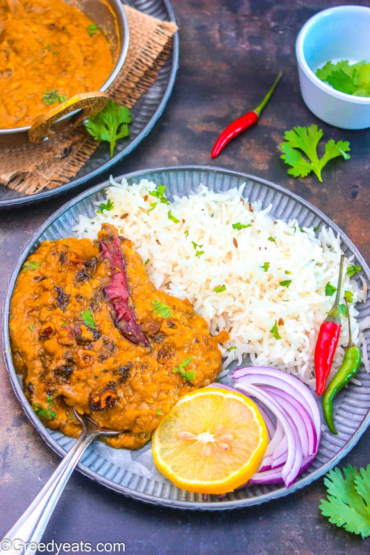 Dal tadka served with rice and onion salad along with sliced lemon and chilies on the side.