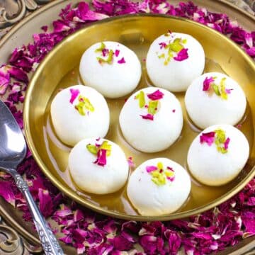 Easy Rasgulla recipe that yields soft and spongy rasgullas that are served in syrup a bronze plate