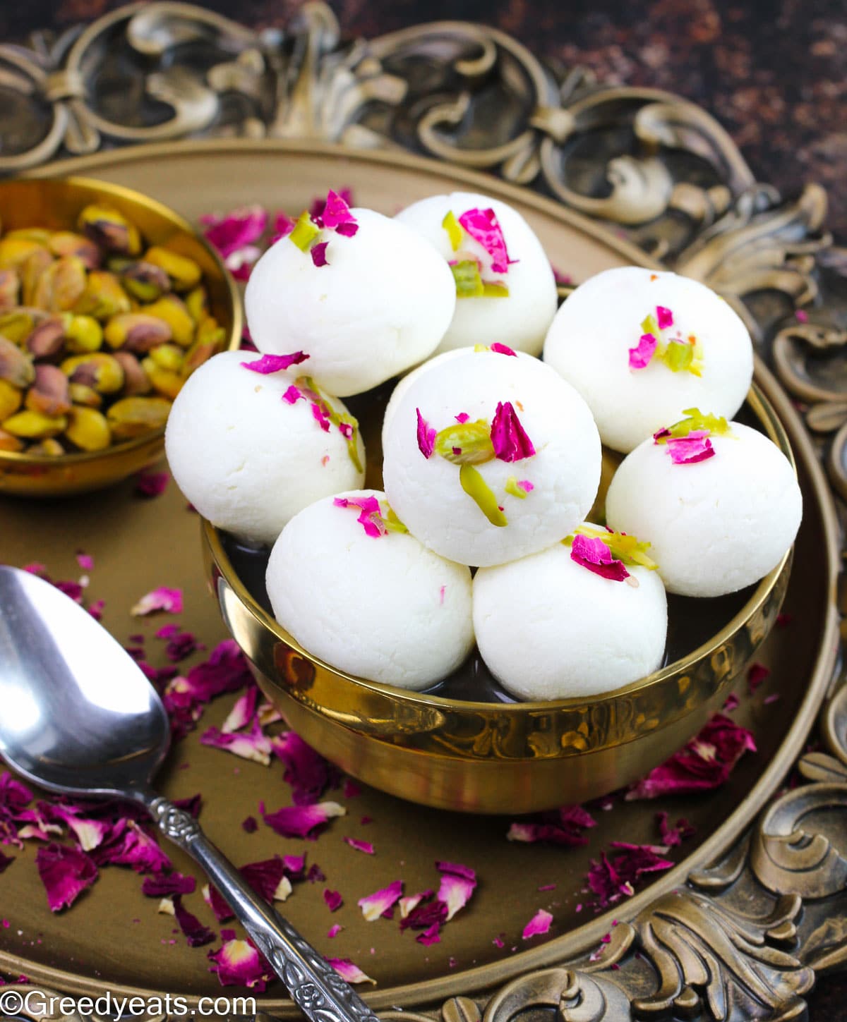 Soft and fluffy Rasulla soaked in sweet rose syrup garnished with slivered pistachios and rose petals.