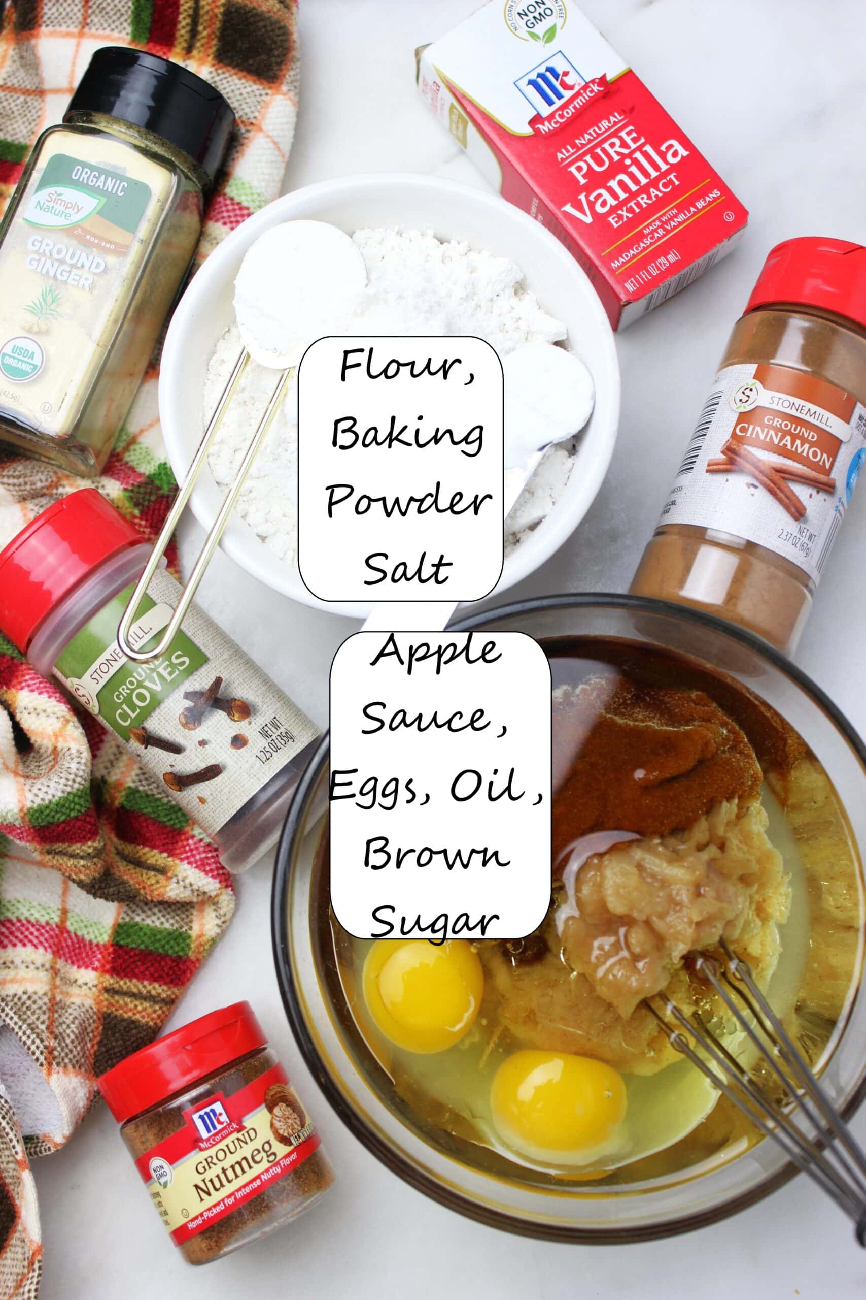 Ingredients like oil, eggs, sugar, flour, leaveners, applesauce and spices to make spice cake.